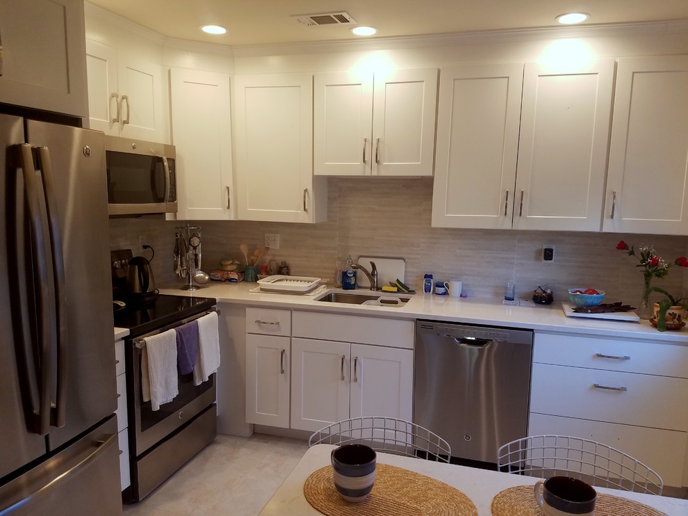 This is an example of a small classic l-shaped kitchen/diner in New York with a submerged sink, shaker cabinets, white cabinets, engineered stone countertops, grey splashback, ceramic splashback, stainless steel appliances and no island.