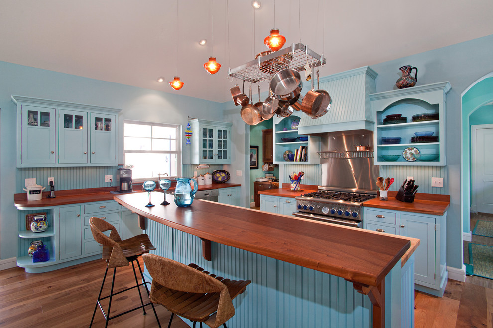 Example of an island style kitchen design in Miami with wood countertops, blue cabinets, shaker cabinets, stainless steel appliances and brown countertops