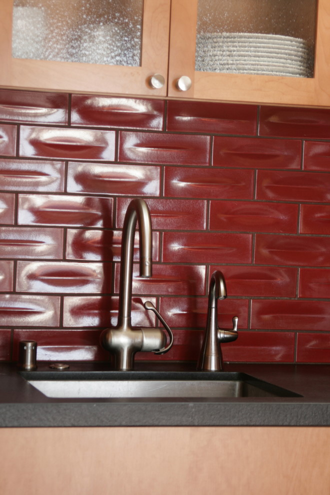 Diseño de cocina minimalista pequeña sin isla con fregadero bajoencimera, armarios con paneles lisos, puertas de armario de madera clara, encimera de granito, salpicadero rojo, salpicadero de azulejos de cerámica, electrodomésticos de acero inoxidable y suelo de madera en tonos medios