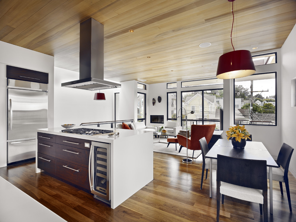 Imagen de cocina contemporánea abierta con electrodomésticos de acero inoxidable y puertas de armario de madera en tonos medios
