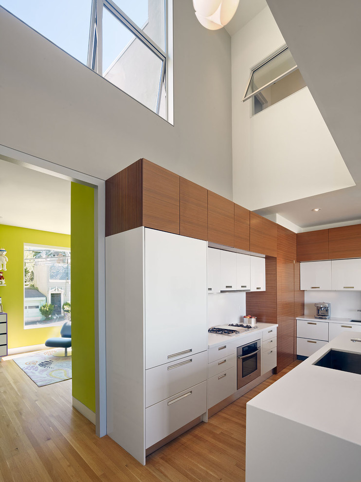 На фото: кухня в стиле модернизм с плоскими фасадами и шторами на окнах