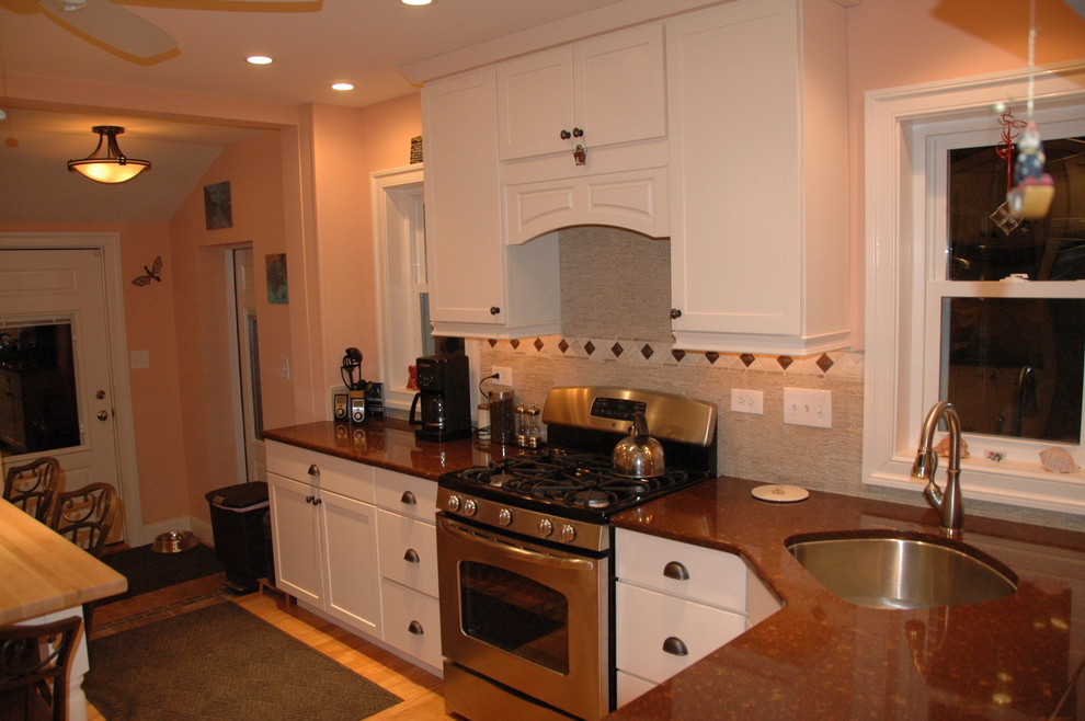 Example of a classic l-shaped eat-in kitchen design in Philadelphia with an undermount sink, recessed-panel cabinets, white cabinets, tile countertops, beige backsplash and stone tile backsplash