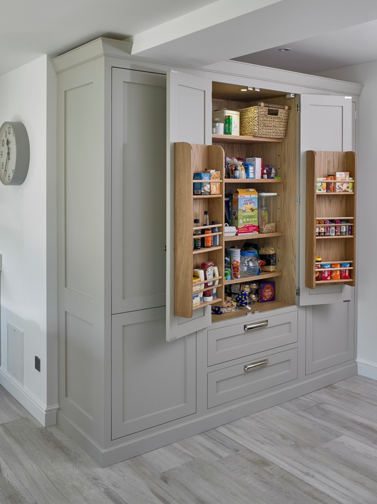 Diseño de cocina comedor lineal clásica renovada de tamaño medio con armarios estilo shaker, puertas de armario grises, suelo gris, fregadero bajoencimera, encimera de cuarcita, salpicadero blanco, electrodomésticos de acero inoxidable, suelo de baldosas de porcelana, una isla y encimeras blancas