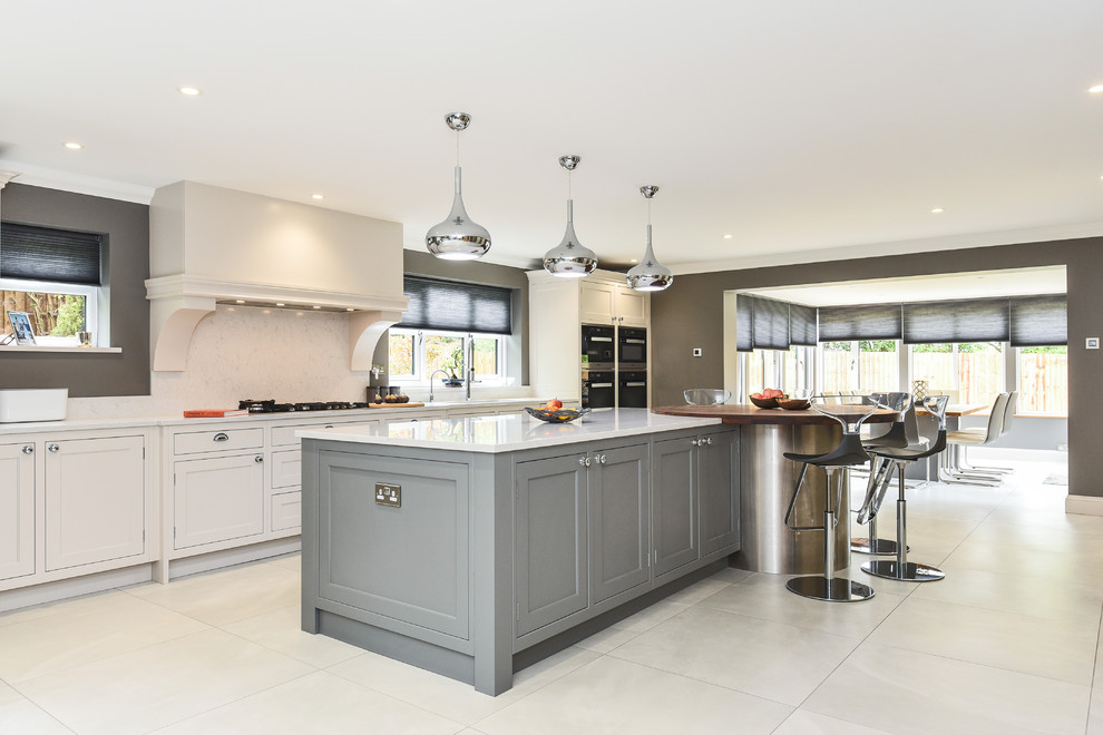 Large classic galley open plan kitchen in Berkshire with a built-in sink, shaker cabinets, grey cabinets, quartz worktops, white splashback, stone slab splashback, integrated appliances, an island and white worktops.