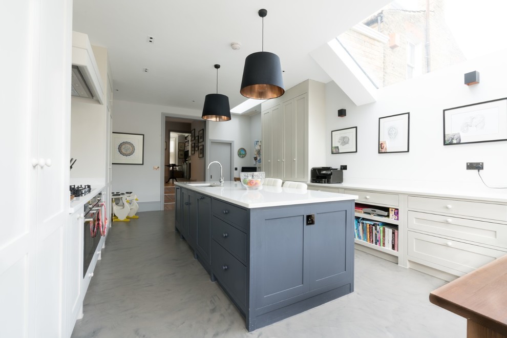Large transitional concrete floor and gray floor kitchen photo in London with shaker cabinets, solid surface countertops, stainless steel appliances, an island, white countertops, an undermount sink and white cabinets