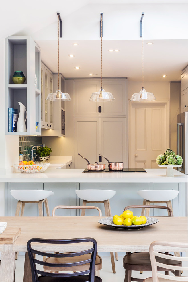 Inspiration for a medium sized contemporary u-shaped kitchen/diner in London with a belfast sink, recessed-panel cabinets, blue cabinets, composite countertops, blue splashback, ceramic splashback, porcelain flooring, an island, white floors and white worktops.