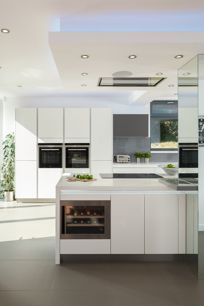 Große Moderne Küche mit flächenbündigen Schrankfronten, weißen Schränken, Küchenrückwand in Grau, Küchengeräten aus Edelstahl und Kücheninsel in Sonstige