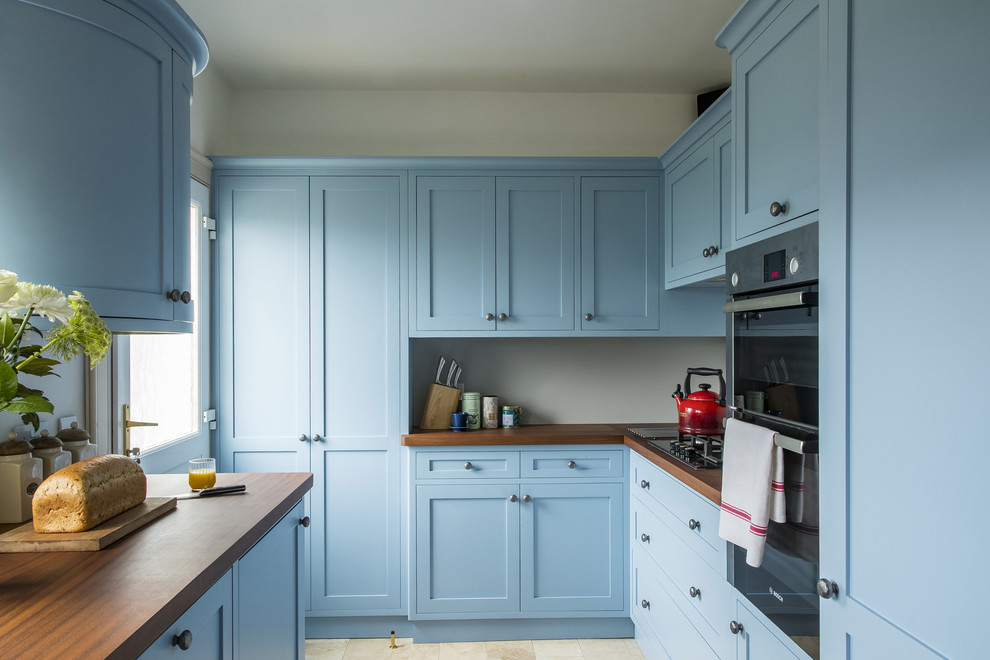 Immagine di una cucina parallela classica chiusa e di medie dimensioni con ante in stile shaker, ante blu, top in legno, paraspruzzi bianco e nessuna isola