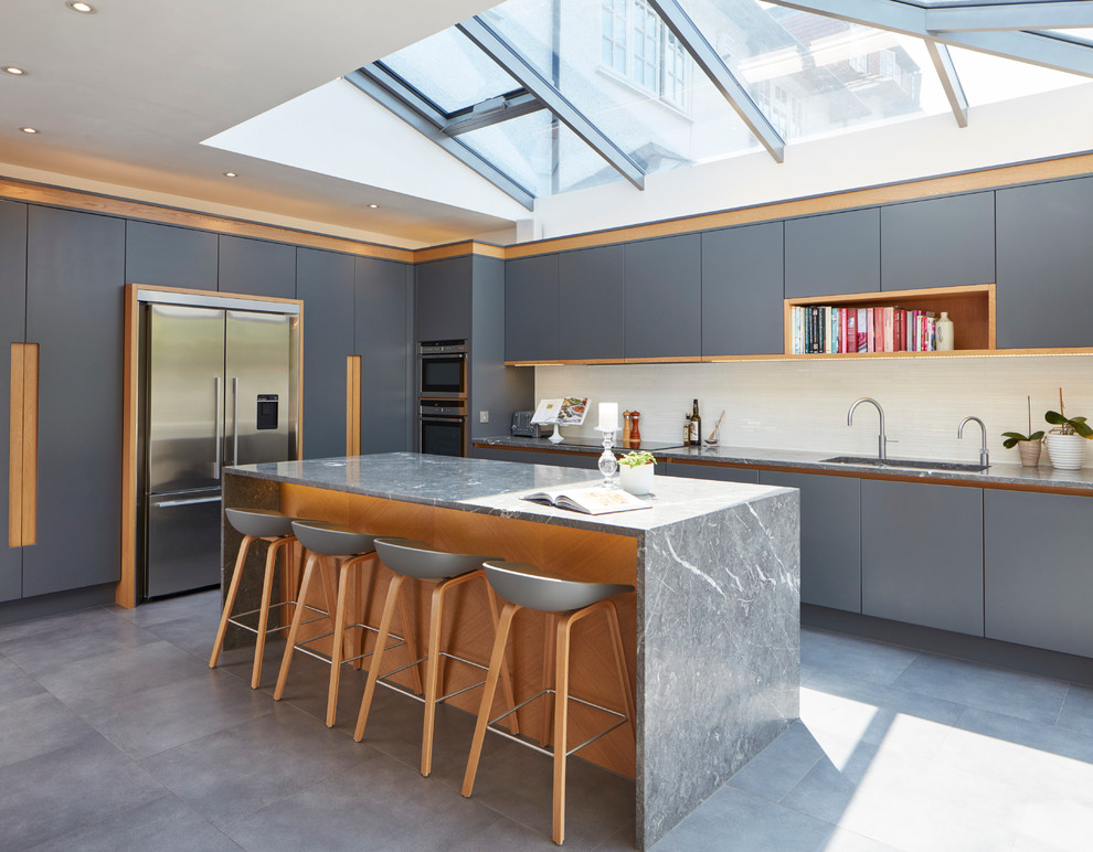 Inspiration for a contemporary kitchen in Berkshire with flat-panel cabinets, grey cabinets, stainless steel appliances, concrete flooring and an island.