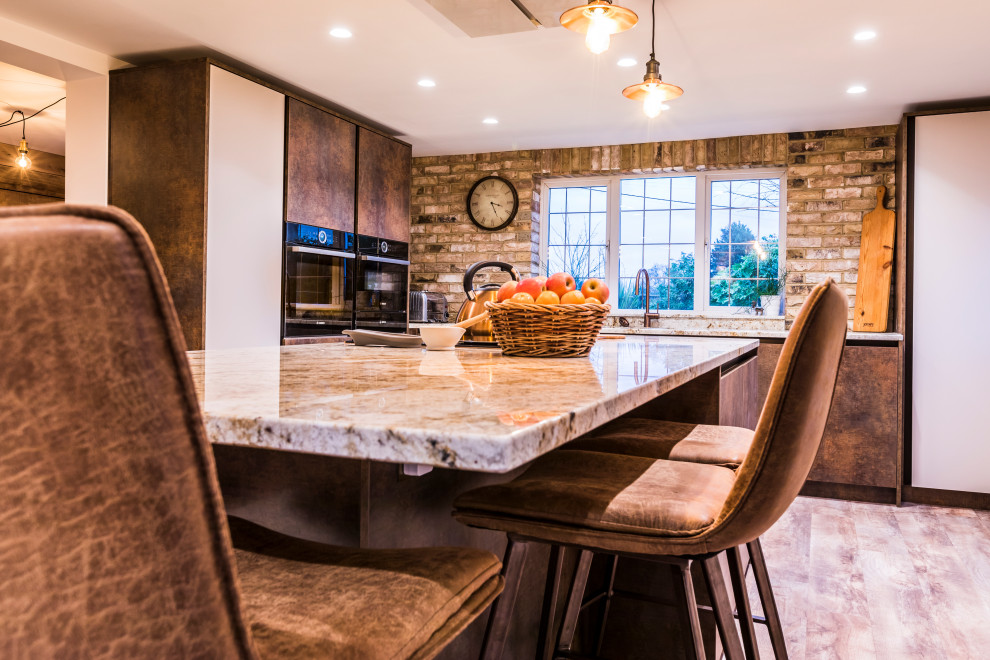 Large trendy l-shaped dark wood floor and brown floor eat-in kitchen photo in Hampshire with a drop-in sink, flat-panel cabinets, distressed cabinets, quartzite countertops, black appliances, an island and white countertops