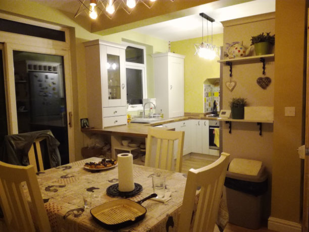 Esempio di una piccola cucina abitabile country con ante bianche, top in legno, elettrodomestici in acciaio inossidabile e pavimento beige
