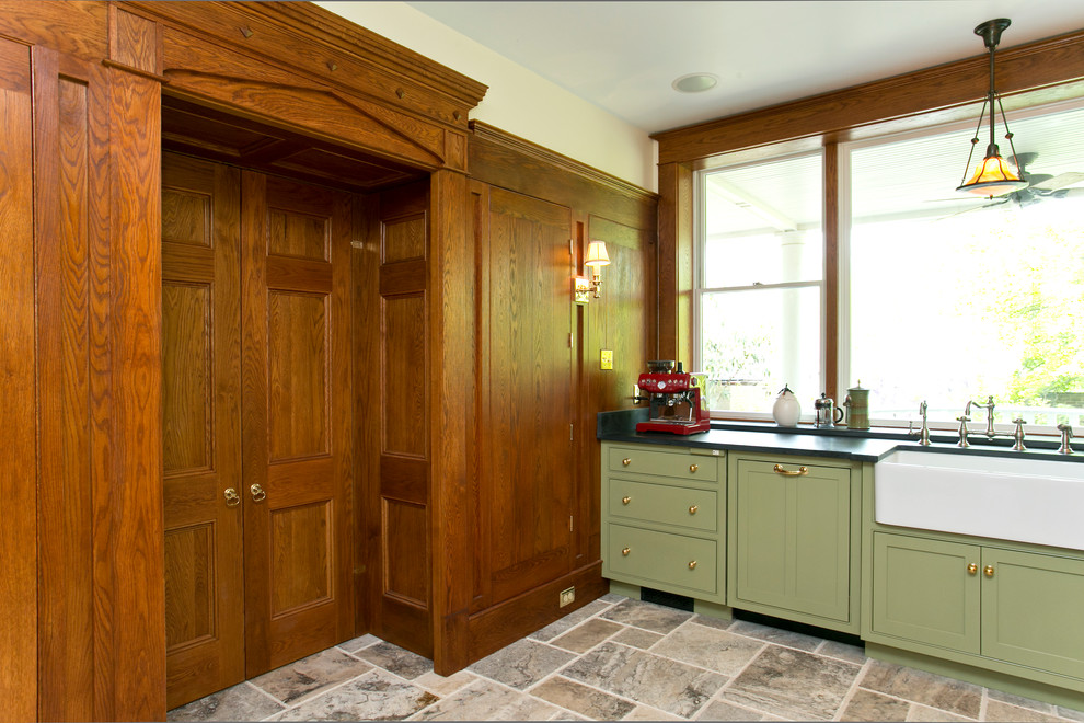 Inspiration for a medium sized classic u-shaped enclosed kitchen in DC Metro with a belfast sink, beaded cabinets, green cabinets, soapstone worktops, beige splashback, ceramic splashback, stainless steel appliances, limestone flooring, an island and brown floors.