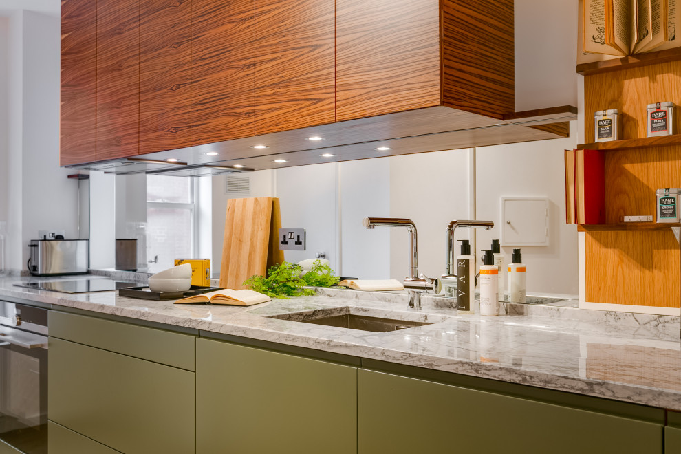 Exempel på ett avskilt, litet modernt grå grått u-kök, med en nedsänkt diskho, gröna skåp, marmorbänkskiva, vitt stänkskydd, spegel som stänkskydd, svarta vitvaror och mellanmörkt trägolv