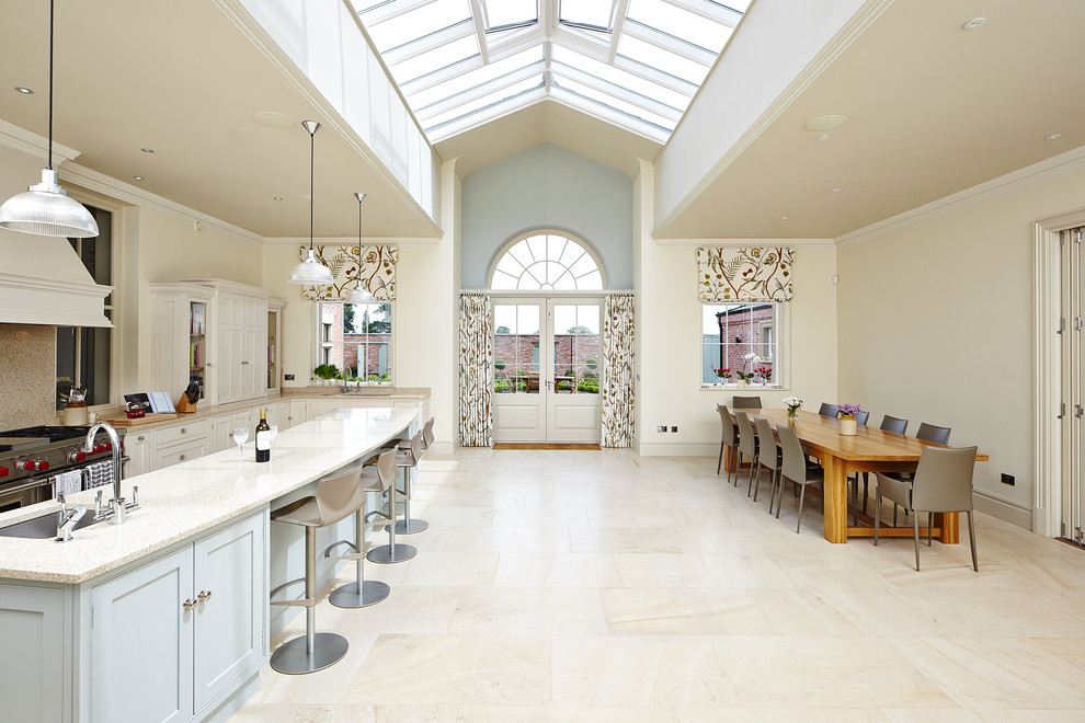 Inredning av ett klassiskt mycket stort kök och matrum, med en undermonterad diskho, vita skåp, rostfria vitvaror och en köksö