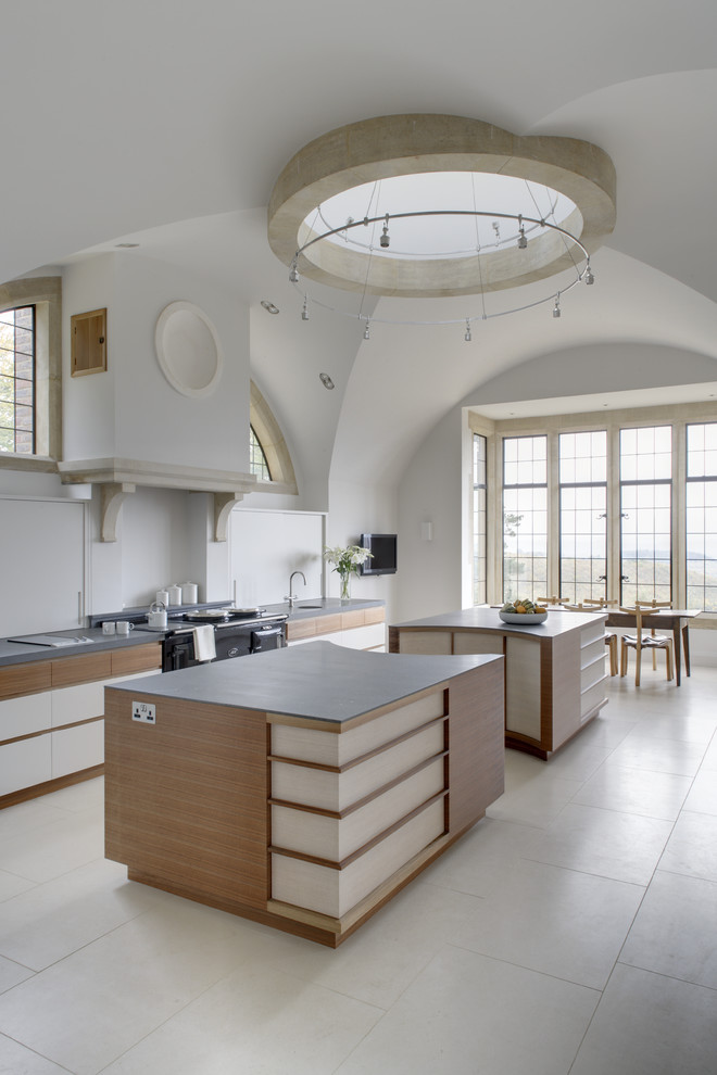 Cette image montre une grande cuisine ouverte design en L avec un plan de travail en granite, 2 îlots et des portes de placard blanches.