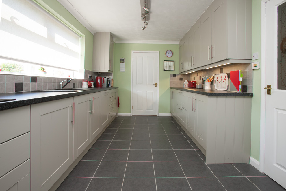 Foto di una cucina parallela design chiusa e di medie dimensioni con ante grigie, paraspruzzi beige, paraspruzzi con piastrelle in ceramica e nessuna isola
