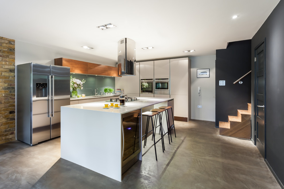 Example of a trendy concrete floor open concept kitchen design in London with flat-panel cabinets, white cabinets, green backsplash, glass sheet backsplash and an island