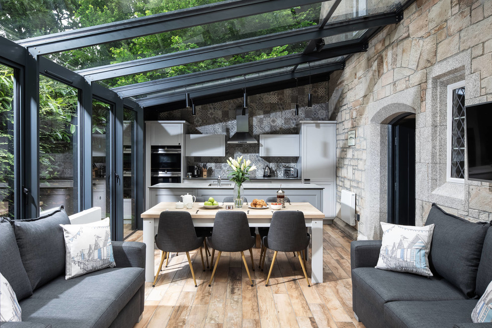 Zweizeilige Klassische Küche mit Schrankfronten im Shaker-Stil, grauen Schränken, Küchenrückwand in Grau, Elektrogeräten mit Frontblende, braunem Holzboden, Kücheninsel und braunem Boden in Cambridgeshire