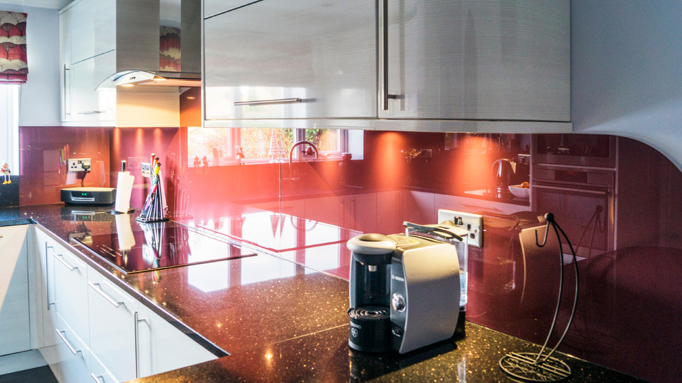 Mittelgroße Moderne Wohnküche in U-Form mit Küchenrückwand in Rot, Glasrückwand und Halbinsel in Essex