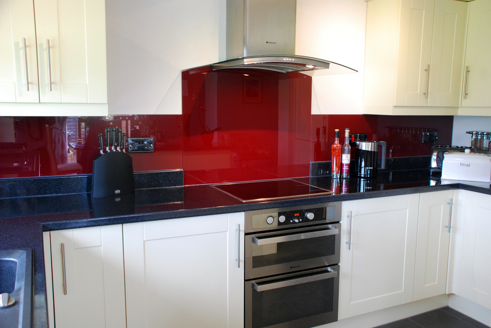 Immagine di una cucina contemporanea di medie dimensioni con ante in stile shaker, ante bianche, paraspruzzi rosso, paraspruzzi con lastra di vetro, elettrodomestici in acciaio inossidabile e pavimento con piastrelle in ceramica