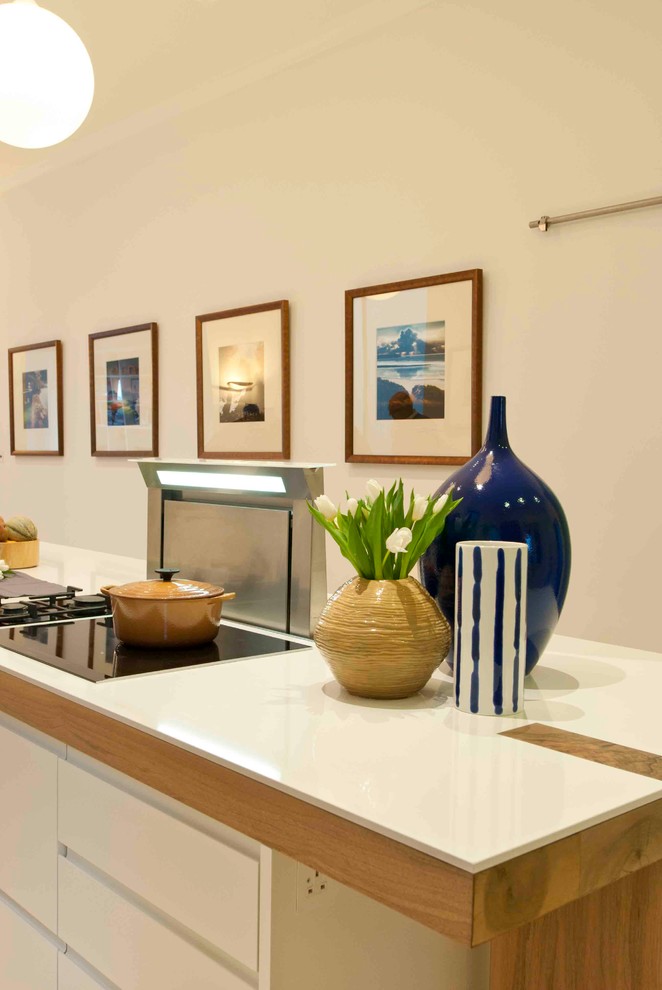 Foto di un'ampia cucina contemporanea con lavello sottopiano, ante lisce, ante in legno scuro, top in quarzo composito, elettrodomestici neri e parquet chiaro