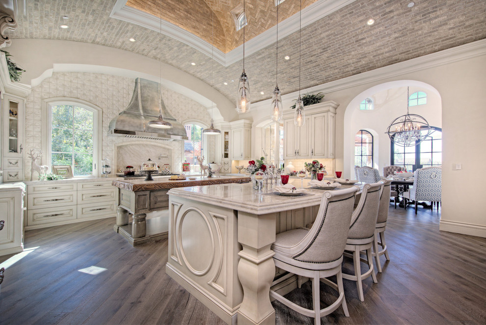 Inspiration for a huge modern u-shaped medium tone wood floor and brown floor enclosed kitchen remodel in Phoenix with a farmhouse sink, raised-panel cabinets, light wood cabinets, quartzite countertops, multicolored backsplash, marble backsplash, paneled appliances, two islands and multicolored countertops