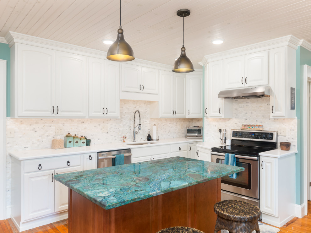 Exemple d'une cuisine en L avec des portes de placard blanches, un plan de travail en quartz, un électroménager en acier inoxydable, un sol en bois brun, îlot et un plan de travail turquoise.