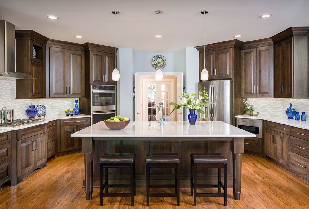 This is an example of a large traditional u-shaped kitchen/diner in DC Metro with a submerged sink, raised-panel cabinets, engineered stone countertops, multi-coloured splashback, mosaic tiled splashback, stainless steel appliances, medium hardwood flooring, an island and dark wood cabinets.