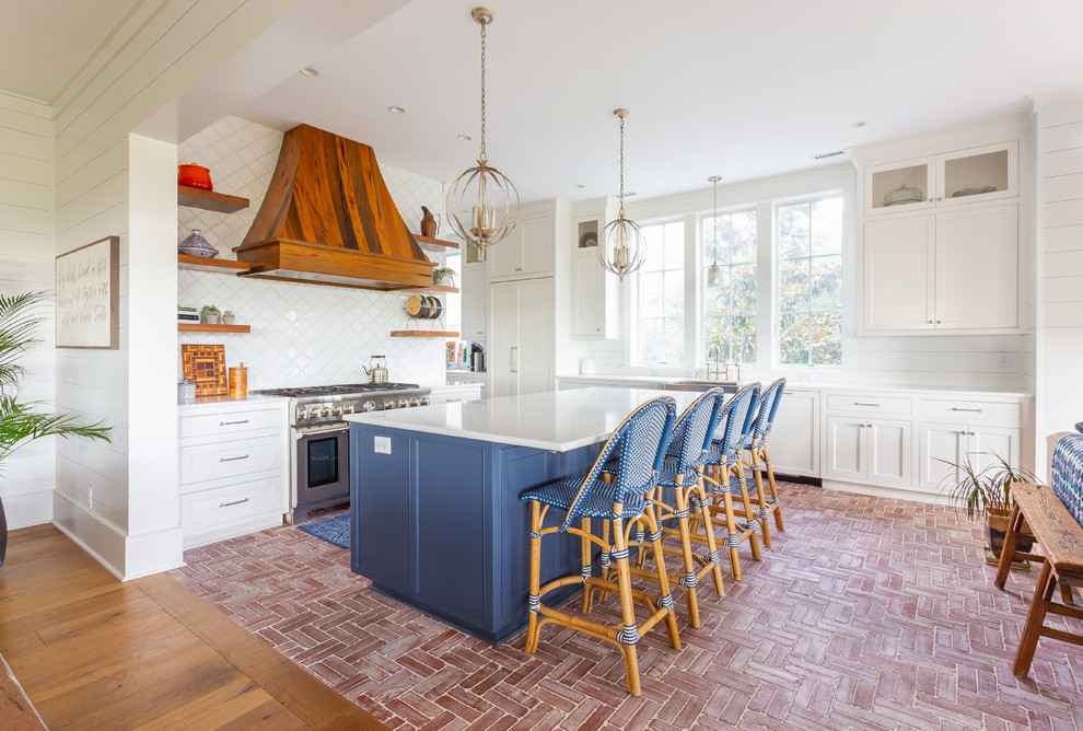 Design ideas for a beach style open plan kitchen in Charleston with a belfast sink, shaker cabinets, white cabinets, white splashback, stainless steel appliances, brick flooring, an island, red floors and white worktops.