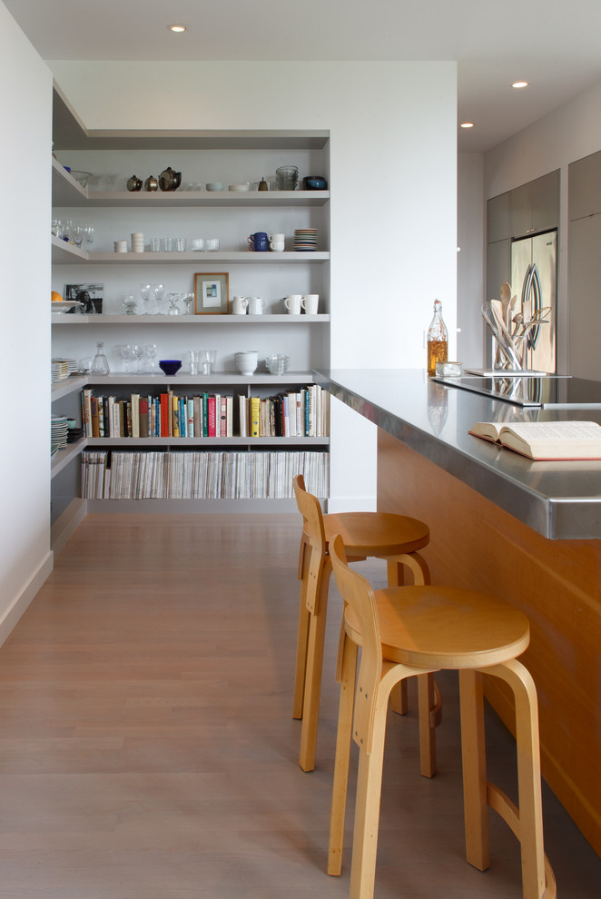 Example of a mid-sized trendy single-wall light wood floor enclosed kitchen design in Seattle with stainless steel countertops, a single-bowl sink, flat-panel cabinets, medium tone wood cabinets, stainless steel appliances and an island