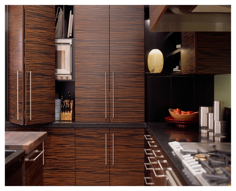 Modern inredning av ett mellanstort kök med öppen planlösning, med en undermonterad diskho, släta luckor, skåp i mörkt trä, granitbänkskiva, grönt stänkskydd, glaspanel som stänkskydd, integrerade vitvaror, mellanmörkt trägolv, en köksö och brunt golv