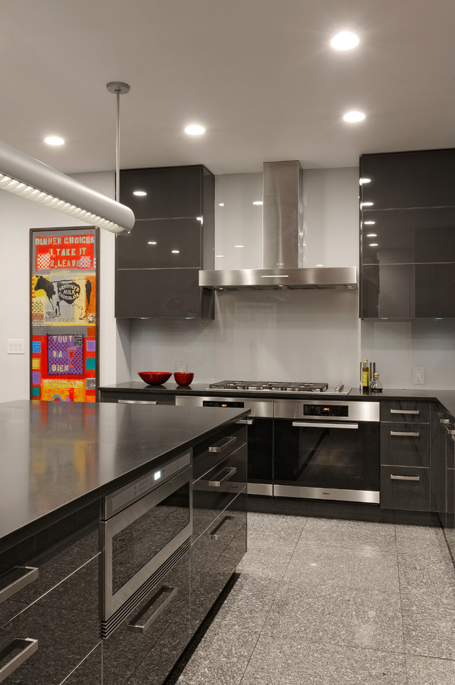 Foto di una grande cucina design con lavello sottopiano, ante lisce, ante nere, top in granito, paraspruzzi grigio, paraspruzzi con lastra di vetro, elettrodomestici in acciaio inossidabile e pavimento in gres porcellanato