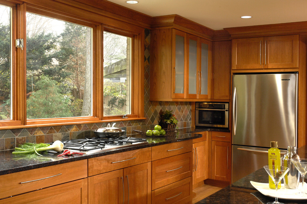Foto på ett stort amerikanskt kök, med en undermonterad diskho, skåp i shakerstil, skåp i mellenmörkt trä, granitbänkskiva, flerfärgad stänkskydd, stänkskydd i stenkakel, rostfria vitvaror, mellanmörkt trägolv och en köksö