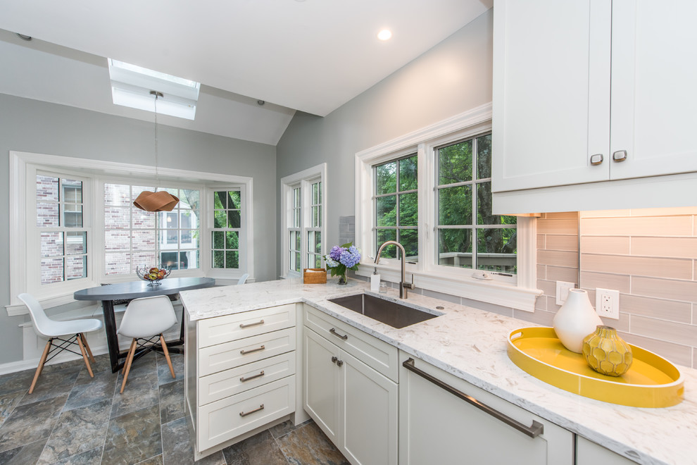 This is an example of a medium sized contemporary galley kitchen/diner in DC Metro with a submerged sink, recessed-panel cabinets, white cabinets, engineered stone countertops, grey splashback, metro tiled splashback, stainless steel appliances, slate flooring, a breakfast bar, multi-coloured floors and white worktops.