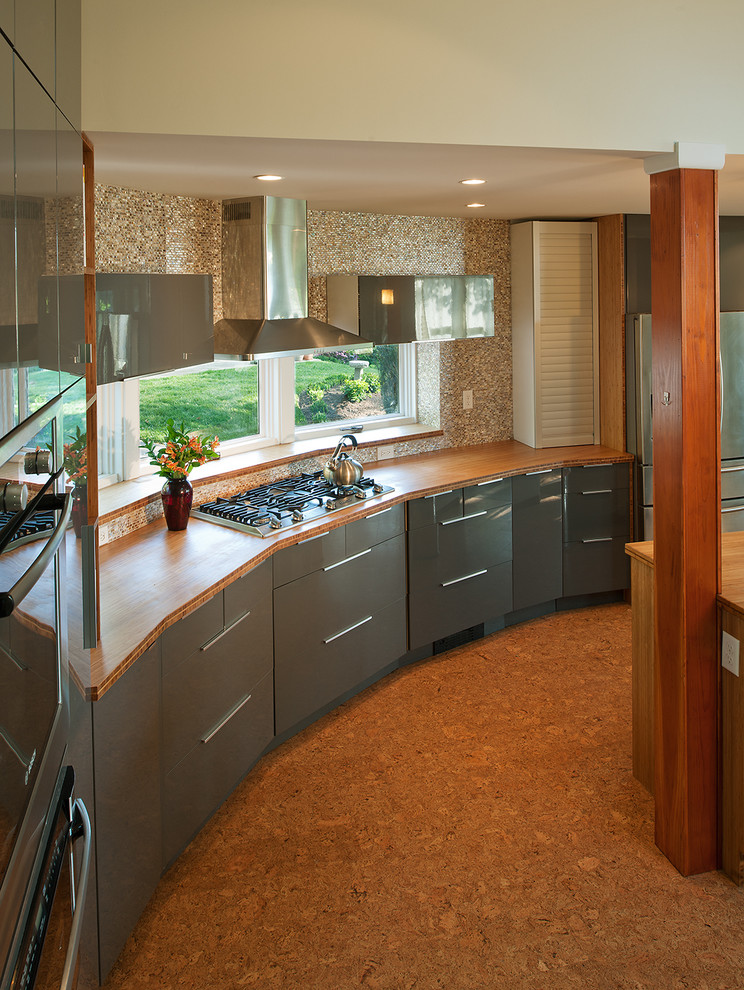 Diseño de cocina contemporánea con electrodomésticos de acero inoxidable, encimera de madera, armarios con paneles lisos, puertas de armario grises y salpicadero marrón
