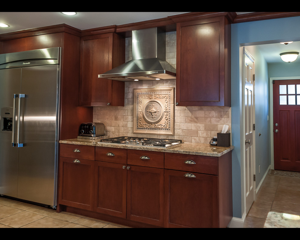 Elegant galley open concept kitchen photo in DC Metro with an undermount sink, raised-panel cabinets, medium tone wood cabinets, soapstone countertops, beige backsplash and stainless steel appliances