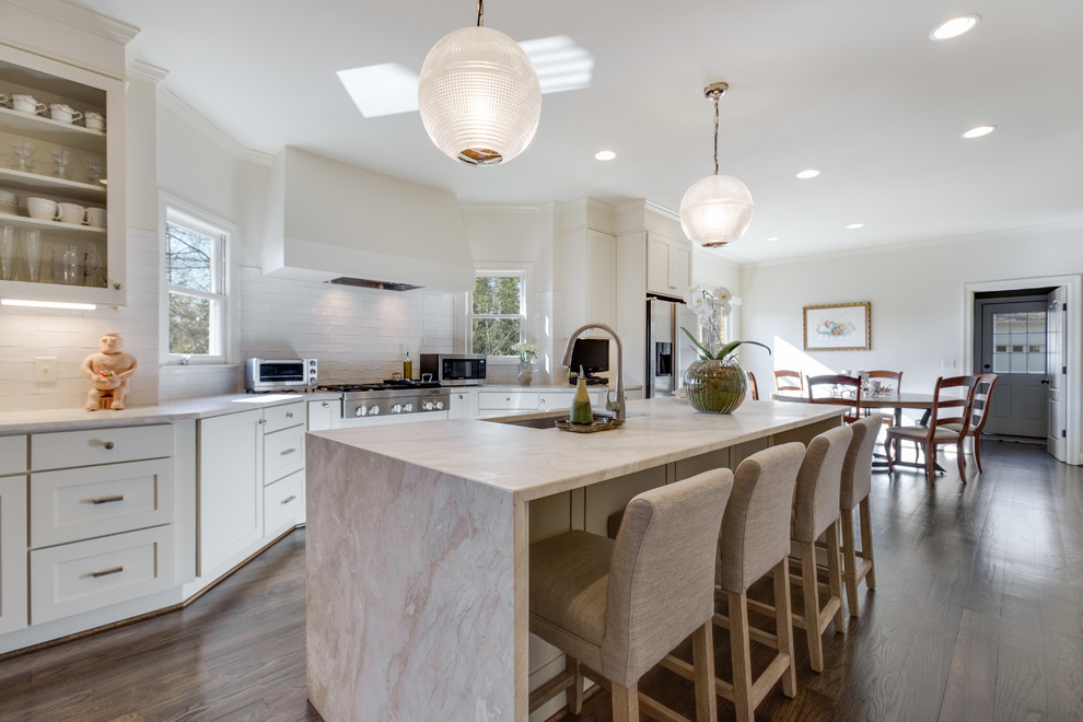 Example of a large minimalist galley medium tone wood floor and brown floor eat-in kitchen design in Birmingham with an undermount sink, recessed-panel cabinets, beige cabinets, marble countertops, beige backsplash, subway tile backsplash, stainless steel appliances, an island and beige countertops