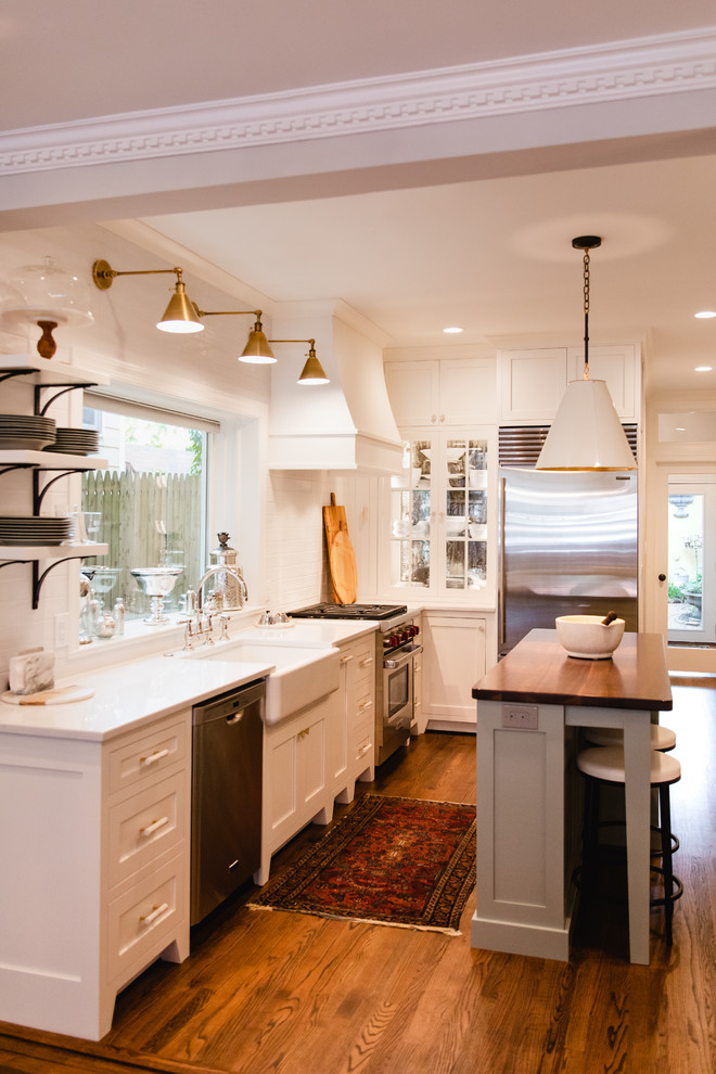 Example of a small transitional l-shaped dark wood floor and brown floor eat-in kitchen design in Baltimore with a farmhouse sink, shaker cabinets, white cabinets, quartz countertops, white backsplash, cement tile backsplash, stainless steel appliances, an island and white countertops
