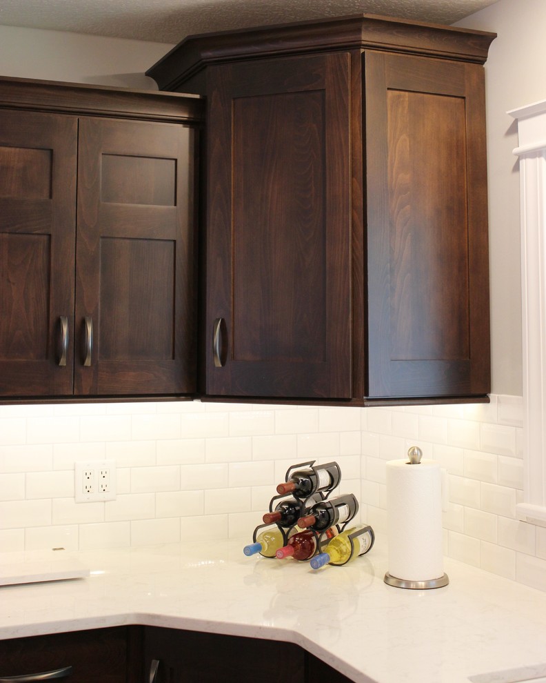 Exempel på ett stort modernt kök, med en undermonterad diskho, släta luckor, skåp i mörkt trä, bänkskiva i kvarts, vitt stänkskydd, stänkskydd i tunnelbanekakel, rostfria vitvaror, mellanmörkt trägolv och en köksö
