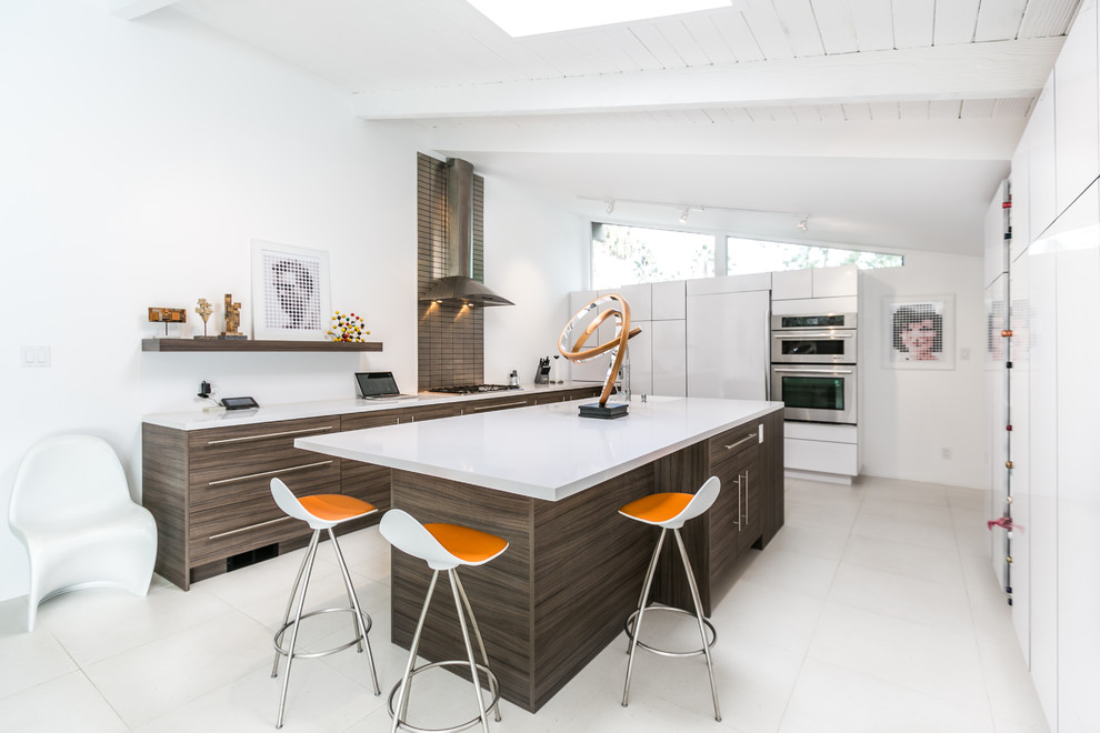 Example of a 1960s u-shaped kitchen design in Seattle with flat-panel cabinets, stainless steel appliances and an island