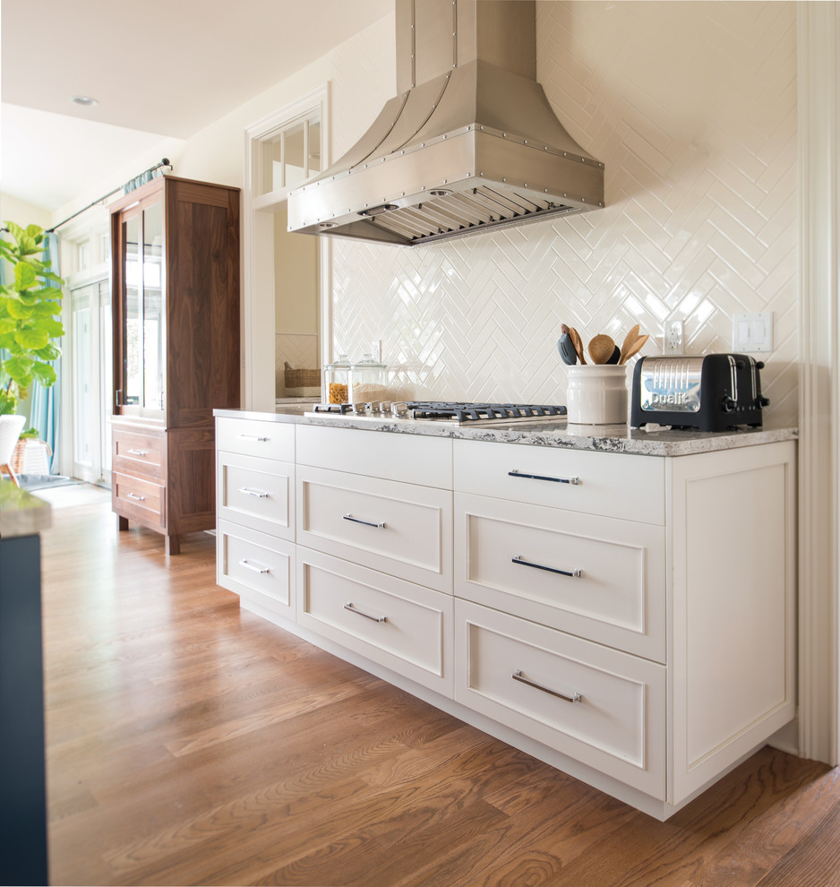 Design ideas for a classic kitchen in Milwaukee with shaker cabinets, white cabinets, white splashback, stainless steel appliances and an island.