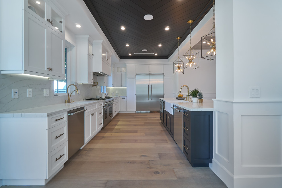 Photo of an expansive contemporary l-shaped kitchen/diner in Los Angeles with shaker cabinets, white cabinets, engineered stone countertops, white splashback, engineered quartz splashback, stainless steel appliances, medium hardwood flooring, an island, brown floors and a wood ceiling.