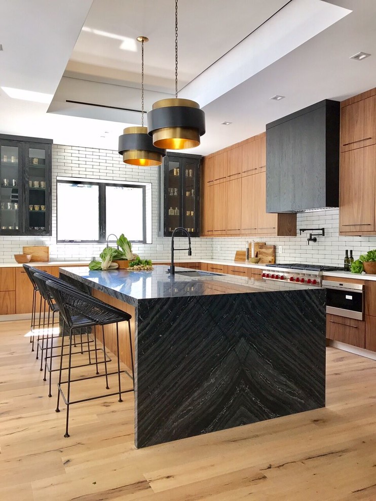 Inspiration for a contemporary l-shaped kitchen remodel in Los Angeles with flat-panel cabinets, stainless steel cabinets, white backsplash, subway tile backsplash, stainless steel appliances and an island