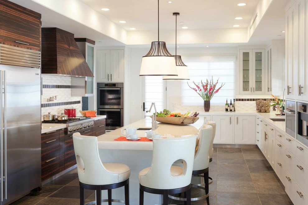 Eat-in kitchen - large contemporary u-shaped eat-in kitchen idea in Los Angeles with an undermount sink, shaker cabinets, white cabinets, solid surface countertops, white backsplash, ceramic backsplash, stainless steel appliances and an island