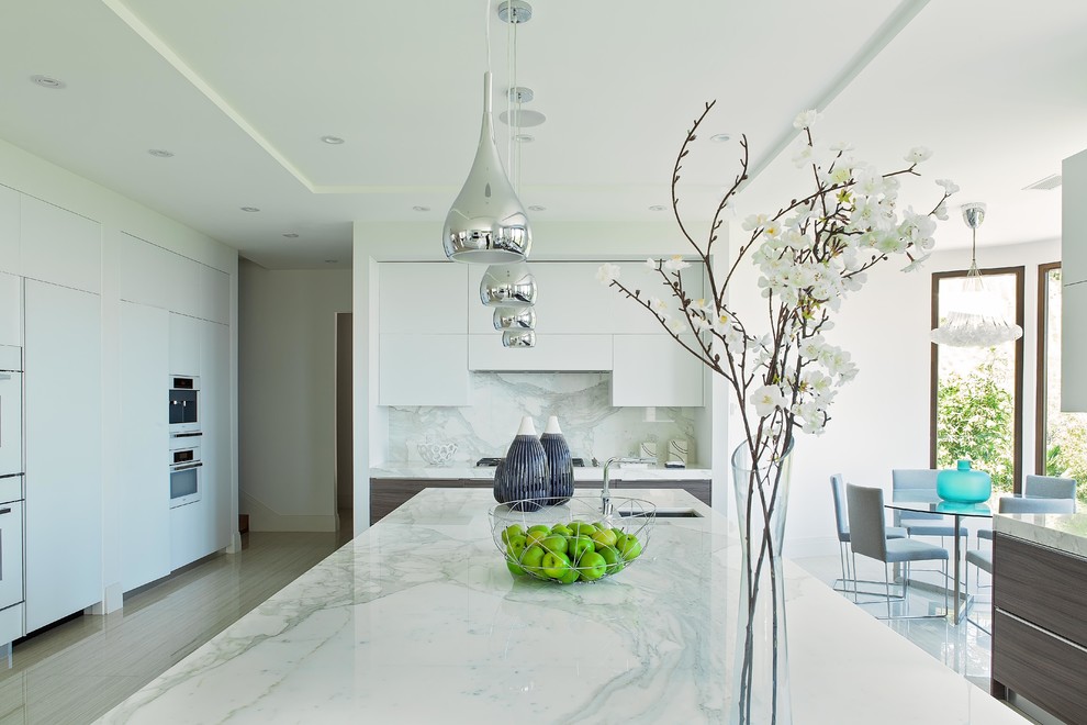 Design ideas for a large contemporary galley enclosed kitchen in Los Angeles with marble worktops, white splashback, stone slab splashback, white appliances and an island.