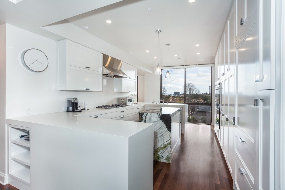 Enclosed kitchen - large modern u-shaped dark wood floor and brown floor enclosed kitchen idea in Los Angeles with recessed-panel cabinets, white cabinets, quartz countertops, stainless steel appliances, an island, white countertops and an undermount sink