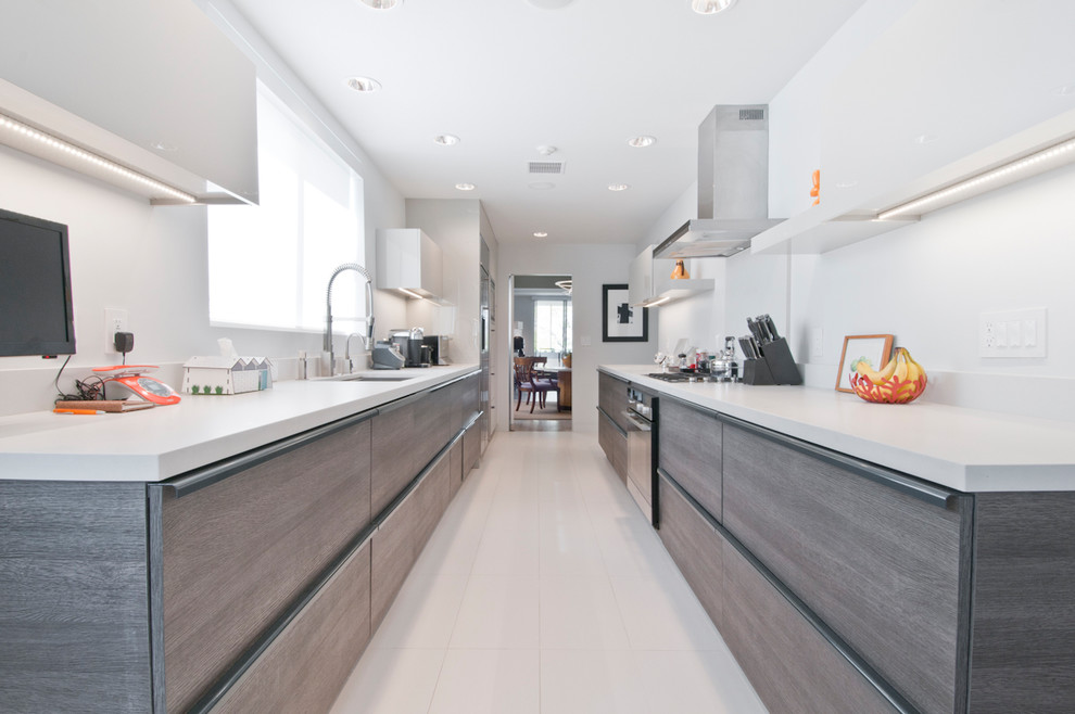 Inredning av ett modernt mellanstort kök, med en undermonterad diskho, släta luckor, grå skåp, bänkskiva i kvartsit, rött stänkskydd, rostfria vitvaror, klinkergolv i porslin och turkost golv