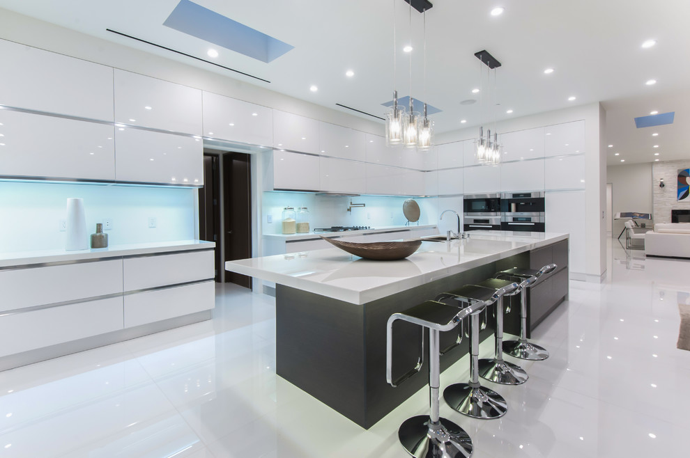 Moderne Küche in L-Form mit Doppelwaschbecken, flächenbündigen Schrankfronten, weißen Schränken, Glasrückwand, Küchengeräten aus Edelstahl und Kücheninsel in Los Angeles