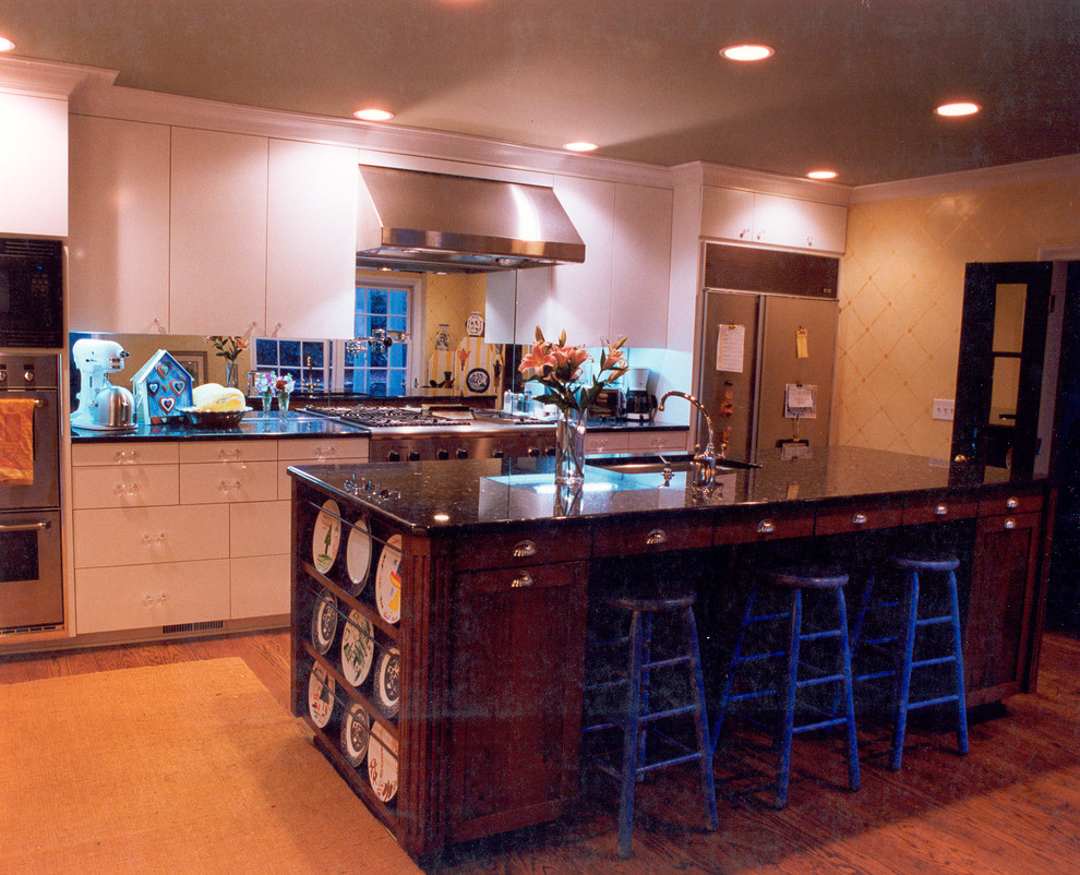 This is an example of a bohemian single-wall enclosed kitchen in Charlotte with a submerged sink, dark wood cabinets, granite worktops and stainless steel appliances.