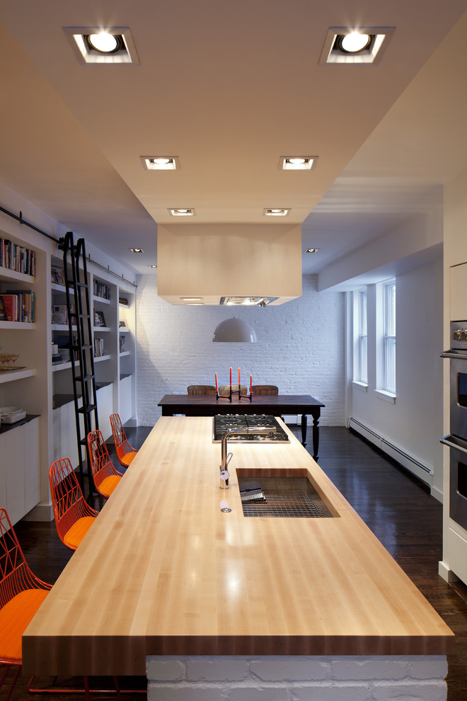 На фото: кухня в стиле модернизм с деревянной столешницей, обеденным столом, врезной мойкой, плоскими фасадами, белыми фасадами, техникой из нержавеющей стали и барной стойкой